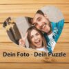 Herzförmiges Fotopuzzle mit Paarfoto und persönlichem Text auf einem Holzuntergrund