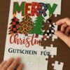 Puzzle-Gutschein als Weihnachtsüberraschung Hände beim Zusammensetzen eines personalisierten Weihnachts-Puzzles mit Gutschein-Feld