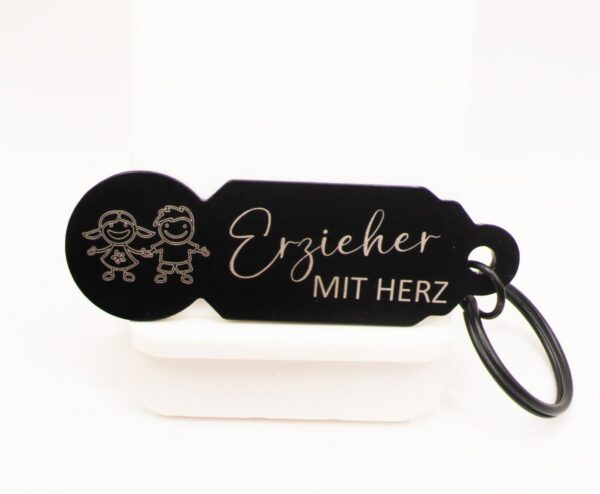 Schwarzer Einkaufswagenlöser mit Erzieher-mit-Herz-Motiv und schwarzem Schlüsselring