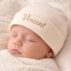Schlafendes Baby mit cremefarbener gerippter Mütze und goldener Namensstickerei Vincent